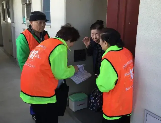 孤立ゼロプロジェクトで軒先を回っているオレンジベストの参加者