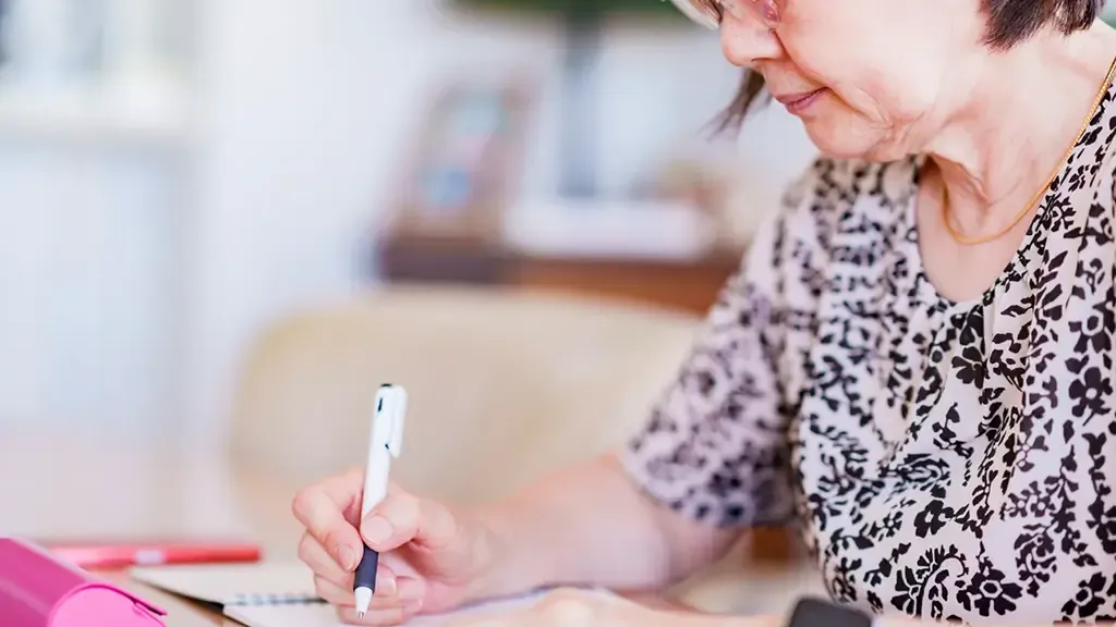 ノートに書き物をしている高齢者