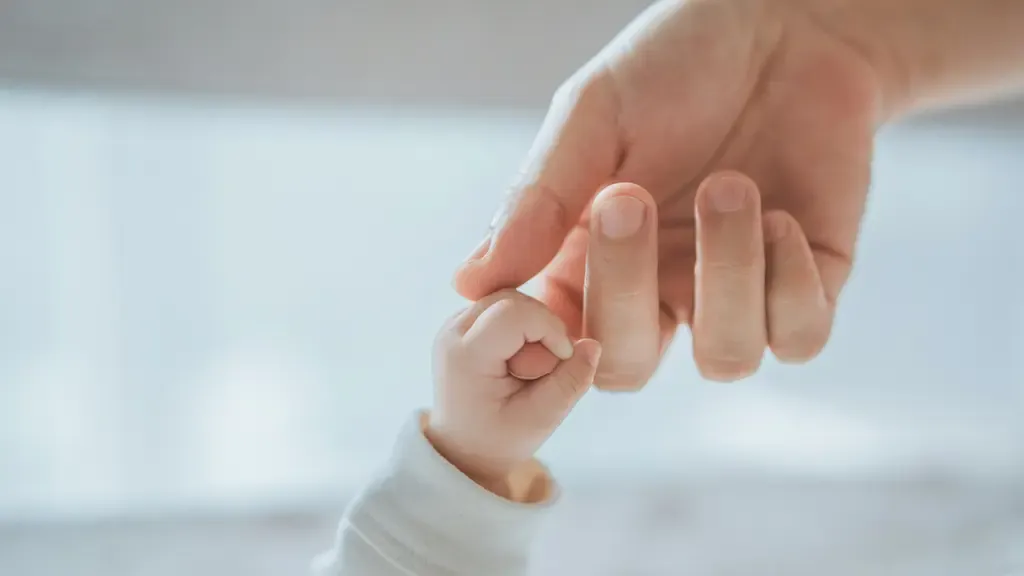 大人の指を握る新生児の手