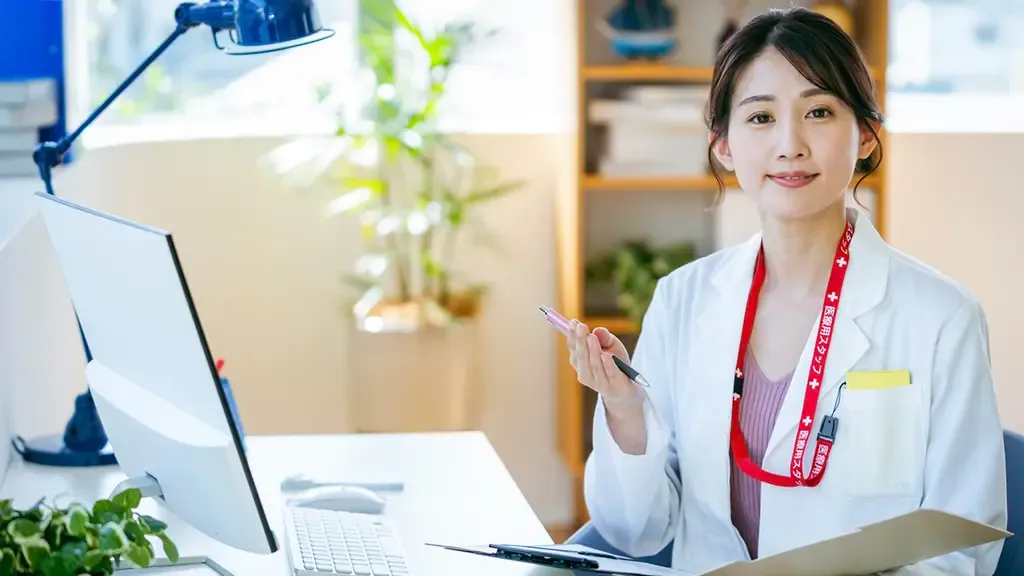 PCが置かれたデスクの前で座って話を聞く医師