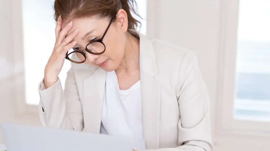 疲れや目のかすみを感じてうつむいている