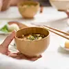 味噌汁のお椀を手に持っている