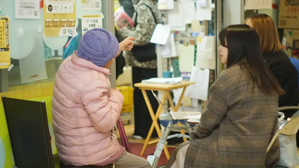 大屋さんが椅子に座って遠くを指し説明している