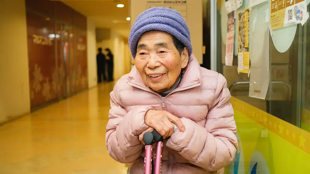 ピンクのダウンを着て取材を受けた笑顔の大屋律子さん