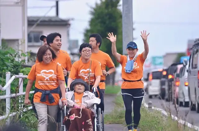 RUN伴の活動で歩道を進むオレンジ色のTシャツの参加者