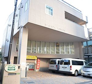 通所施設「は～と・ピア 2」の外観。入口奥には、施設看板と並んで、「お弁当」と書かれた赤いのぼりが立てられている。