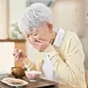 右手に箸を持ち左手を口にあてる