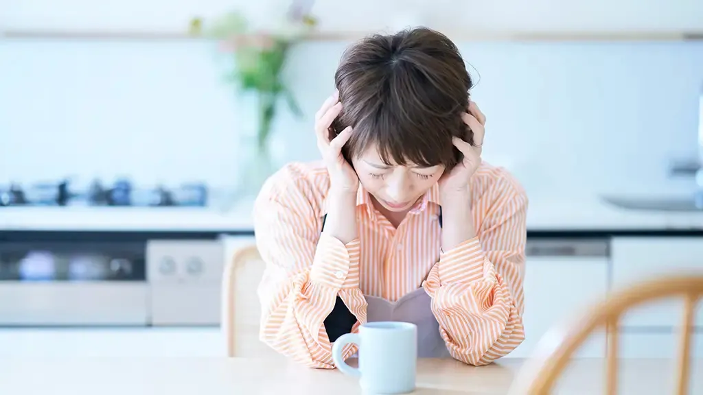 机でうつむき顔をしかめる人